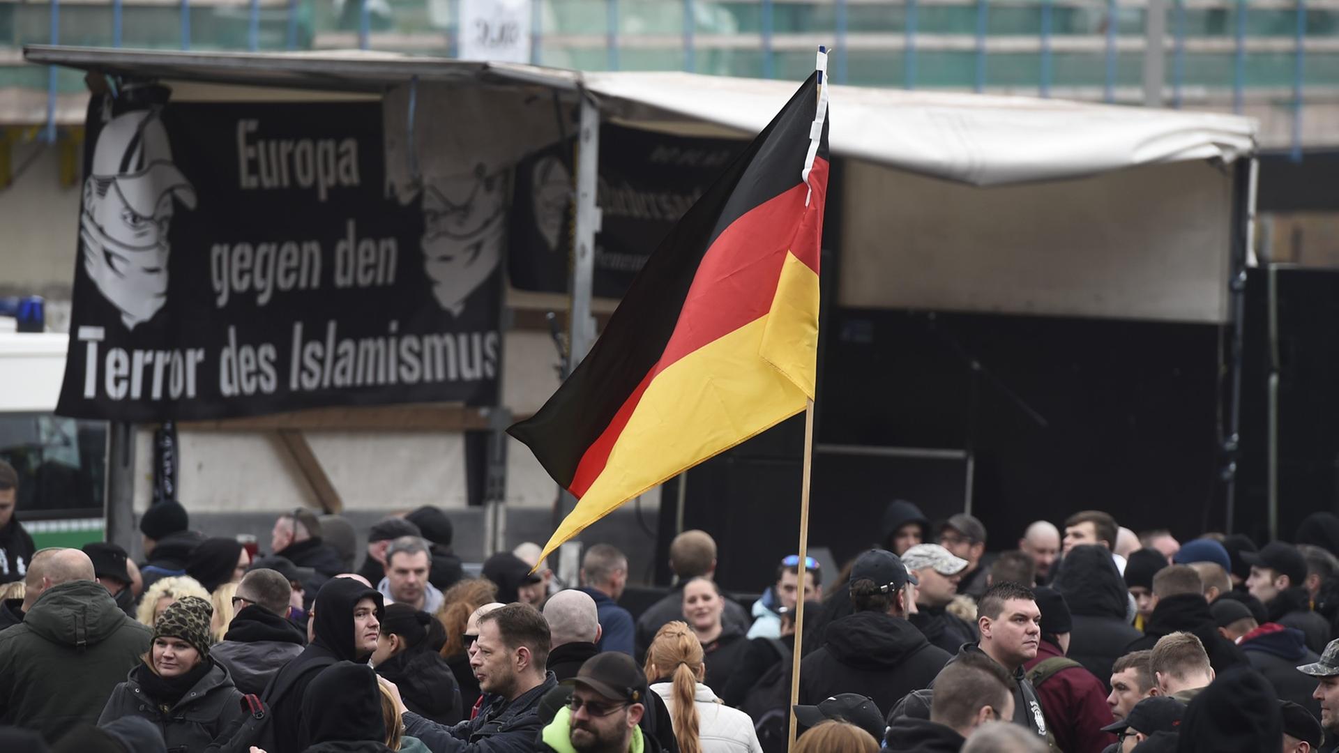 GERMANY, HANOVER : A participant holds up a German flag as far-right hooligans rally against Islamist extremism under the banner 'Hooligans against Salafism' (HoGeSa) at the former central bus station near the main train station, on November 15, 2014 in Hanover, central Germany. Around 5000 hooligans are expected to take part in the rally. AFP PHOTO / ODD ANDERSEN GERMANY, HANOVER : A participant holds up a German flag as far-right hooligans rally against Islamist extremism under the banner 'Hooligans against Salafism' (HoGeSa) at the former central bus station near the main train station, on November 15, 2014 in Hanover, central Germany. Around 5000 hooligans are expected to take part in the rally. AFP PHOTO / ODD ANDERSEN