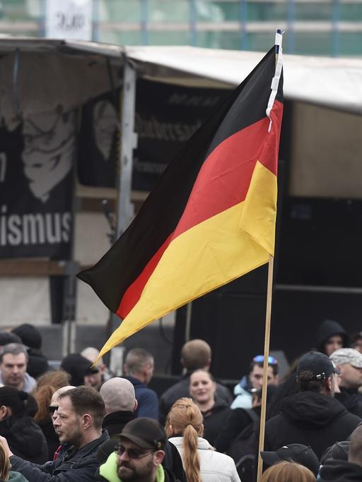 GERMANY, HANOVER : A participant holds up a German flag as far-right hooligans rally against Islamist extremism under the banner 'Hooligans against Salafism' (HoGeSa) at the former central bus station near the main train station, on November 15, 2014 in Hanover, central Germany. Around 5000 hooligans are expected to take part in the rally. AFP PHOTO / ODD ANDERSEN