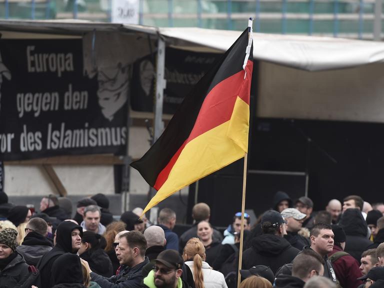 GERMANY, HANOVER : A participant holds up a German flag as far-right hooligans rally against Islamist extremism under the banner 'Hooligans against Salafism' (HoGeSa) at the former central bus station near the main train station, on November 15, 2014 in Hanover, central Germany. Around 5000 hooligans are expected to take part in the rally. AFP PHOTO / ODD ANDERSEN