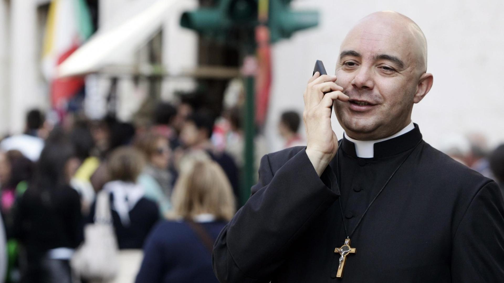 Ein Priester im Vatikan telefoniert mit einem Smartphone. Ein Priester im Vatikan telefoniert mit einem Smartphone.