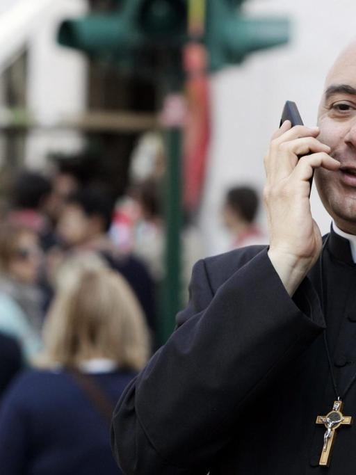 Ein Priester im Vatikan telefoniert mit einem Smartphone.