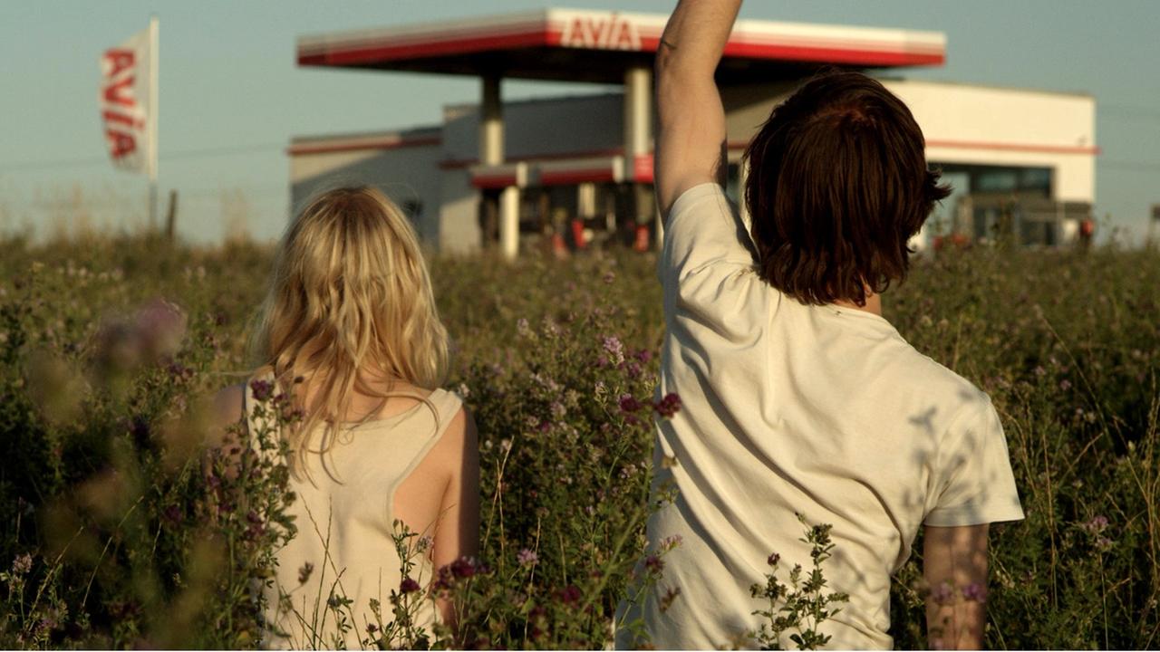 Die Zwillinge Elena (Julia Zange) und Robert (Josef Mattes) auf einer Wiese mit Blick auf eine Tankstelle im Hintergrund. Die Zwillinge Elena (Julia Zange) und Robert (Josef Mattes) auf einer Wiese mit Blick auf eine Tankstelle im Hintergrund.