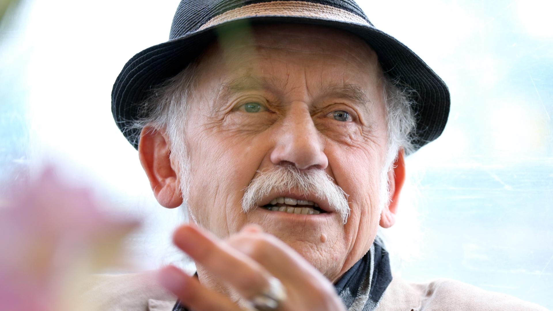 Tilo Prückner trägt einen Hut und gestikuliert. Tilo Prückner trägt einen Hut und gestikuliert.