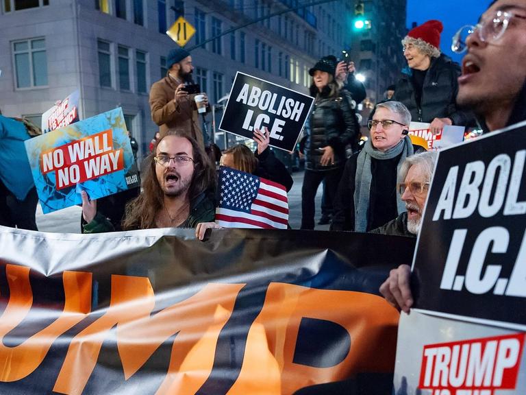 Empörte Aktivisten halten Transparente mit Anti-Trump-Parolen in die Luft.