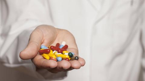 Ein Arzt hält Tabletten in der Hand.
