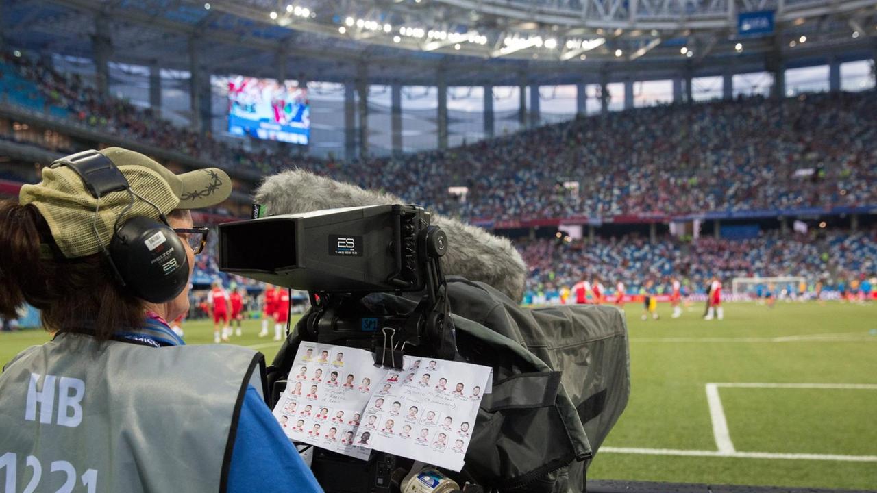 Eine Kamerafrau an einer Fernsehkamera am Rande eines Fußballfeldes