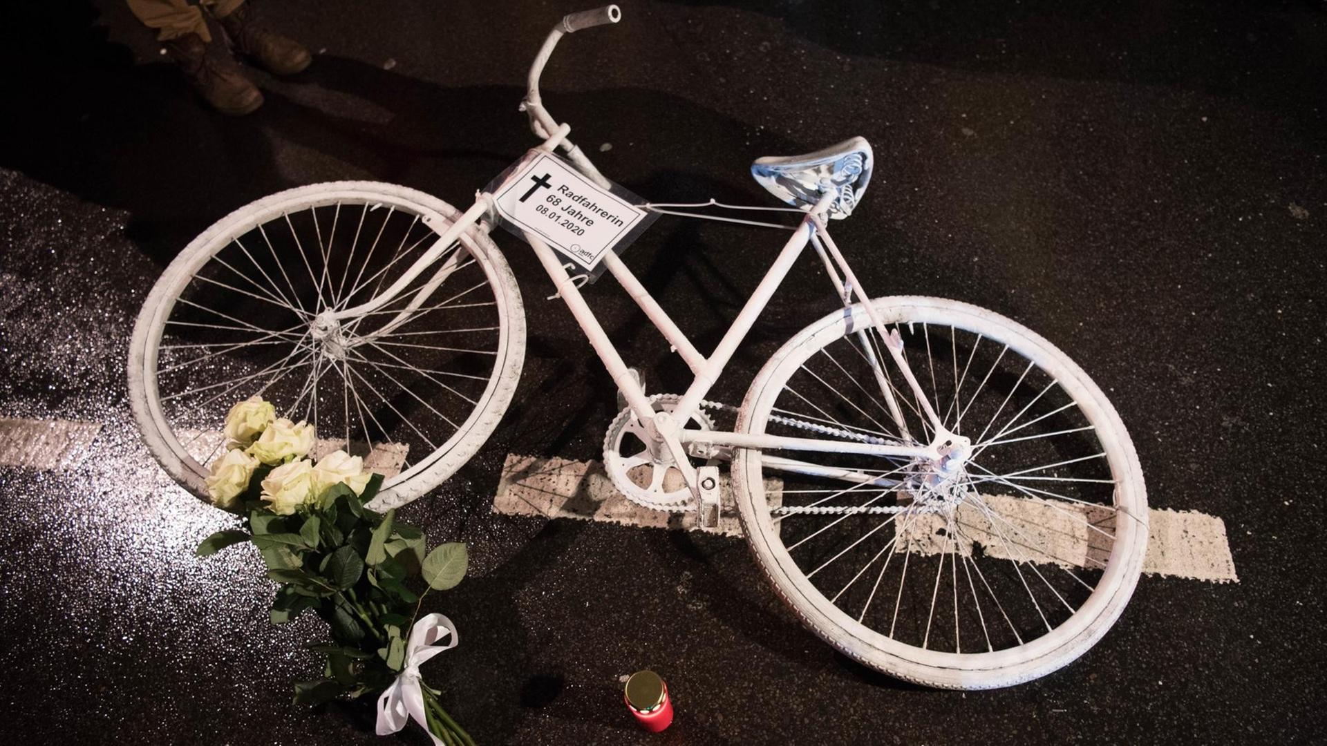 Ein weißes Rad und Blumen liegen auf einer Straße. Ein weißes Rad und Blumen liegen auf einer Straße.