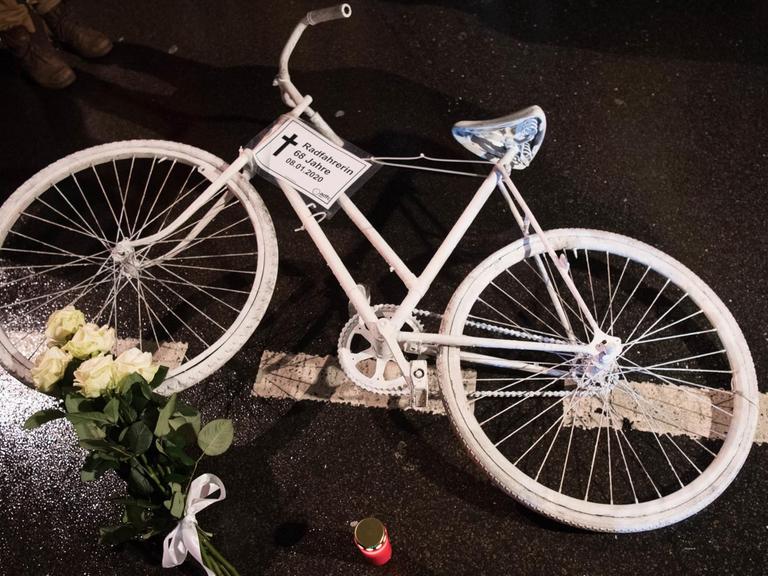 Ein weißes Rad und Blumen liegen auf einer Straße.
