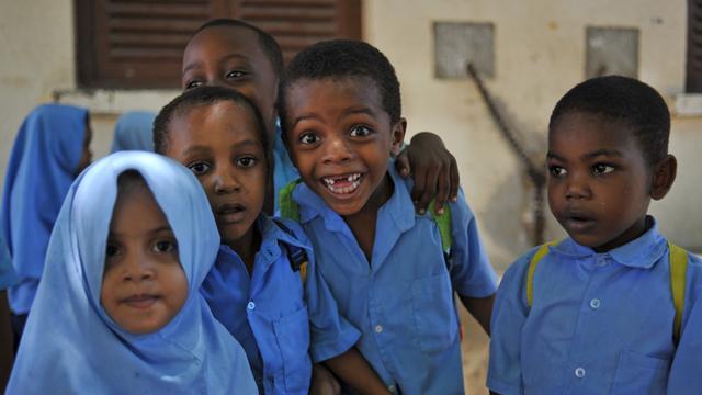 Kinder in Schuluniform stehen vor einem Haus in Stonetown, der Altstadt von Sansibar.