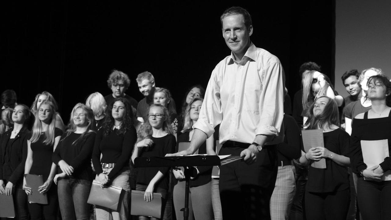 Der Dirigent steht vor dem Chor, kurz nach einer gemeinsamen Verbeugung. Der Dirigent steht vor dem Chor, kurz nach einer gemeinsamen Verbeugung.