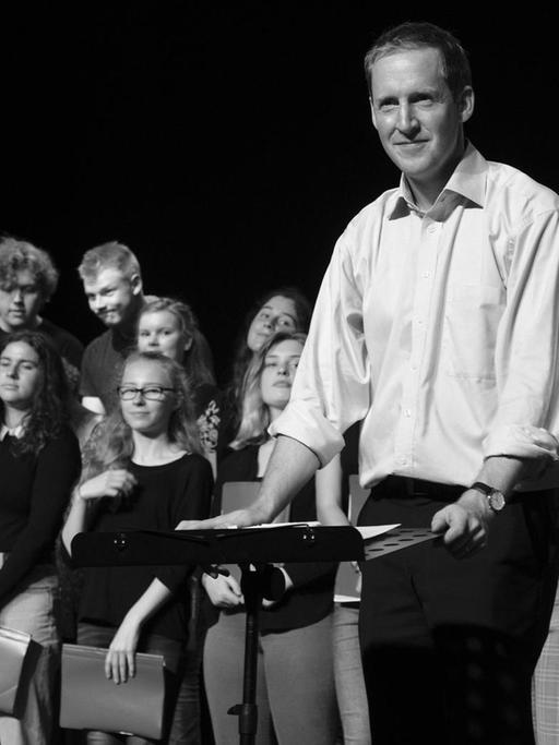 Der Dirigent steht vor dem Chor, kurz nach einer gemeinsamen Verbeugung.