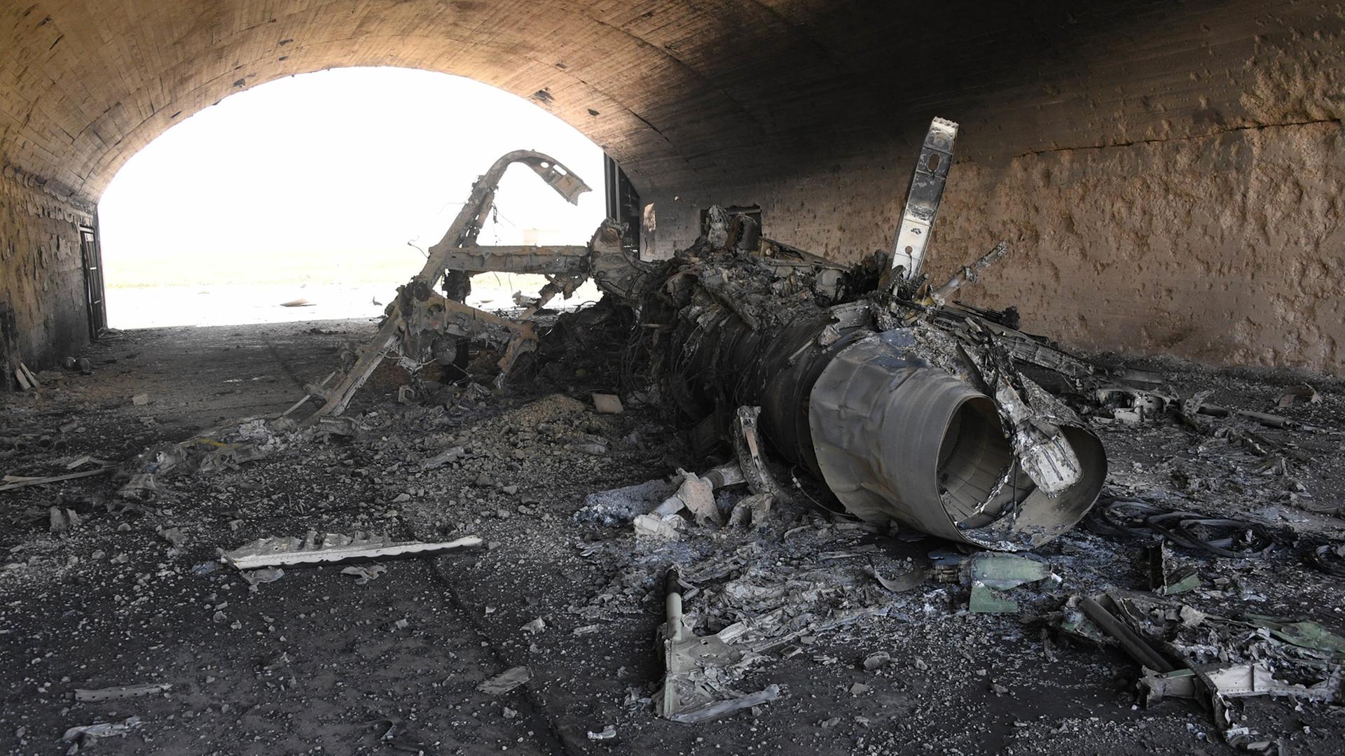 Ein zerstörtes Flugzeug liegt nach dem US-Luftangriff auf einen Luftwaffenstützpunkt der syrischen Armee auf dem Boden. Ein zerstörtes Flugzeug liegt nach dem US-Luftangriff auf einen Luftwaffenstützpunkt der syrischen Armee auf dem Boden.
