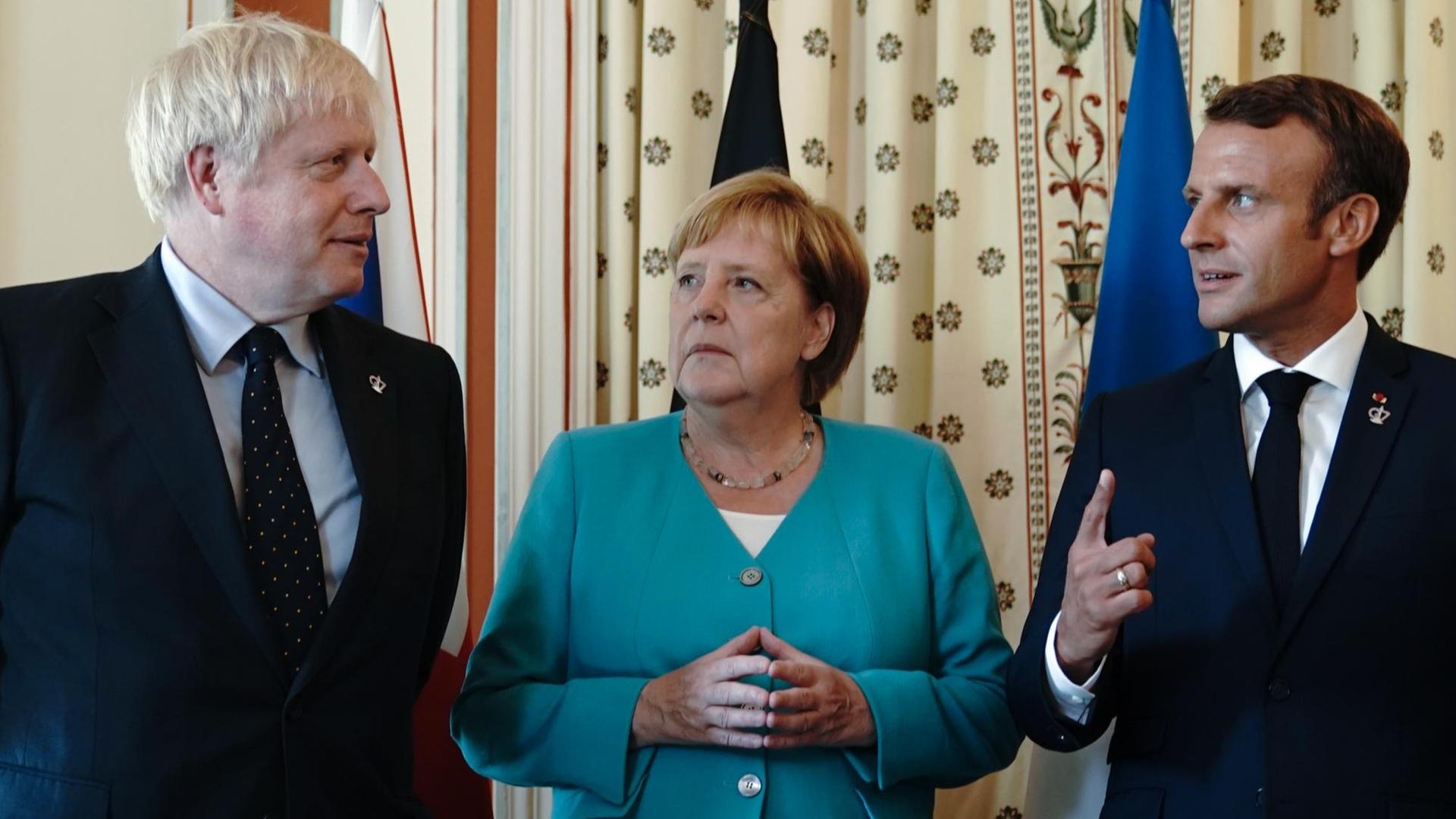 24.08.2019, Frankreich, Biarritz: Bundeskanzlerin Angela Merkel (CDU), steht zwischen Boris Johnson (l), Premierminister von Großbritannien, und Emmanuel Macron, Präsident von Frankreich 24.08.2019, Frankreich, Biarritz: Bundeskanzlerin Angela Merkel (CDU), steht zwischen Boris Johnson (l), Premierminister von Großbritannien, und Emmanuel Macron, Präsident von Frankreich