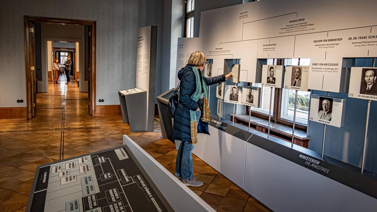 Besucher der Ausstellung stehen vor Informationstafeln