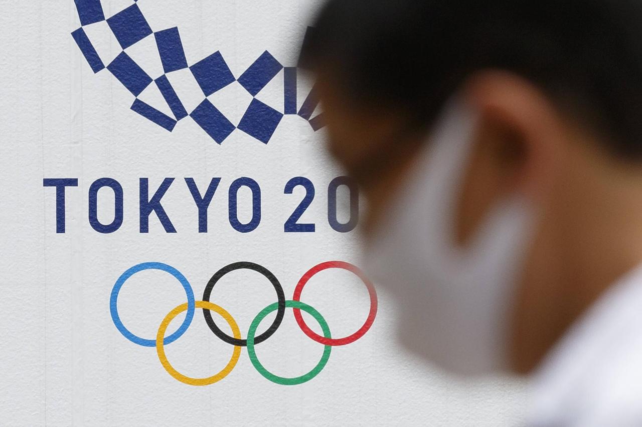 Ein Man mit Gesichtsmaske geht an einem Logo für die Olympischen Spiele in Tokio 2020 vorbei. Ein Man mit Gesichtsmaske geht an einem Logo für die Olympischen Spiele in Tokio 2020 vorbei.