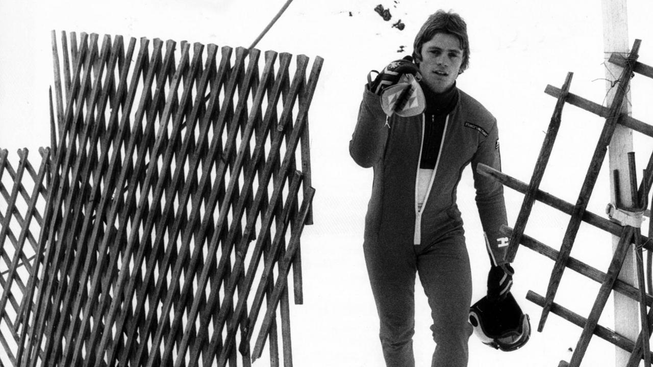 Schwarz-weiß-Aufnahme des DDR-Sportlers Claus Tuchscherer, der seine Ski auf der Schulter trägt 