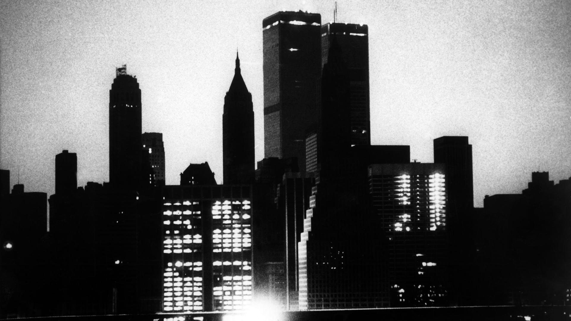Die schwarz-weiße Silhouette New Yorks mit nur wenigen beleuchteten Fenstern: Nur wenige Notbeleuchtungen funktionierten im Juli 1977, als ein gigantischer Stromausfall New Yorks Lichter ausgehen ließ.