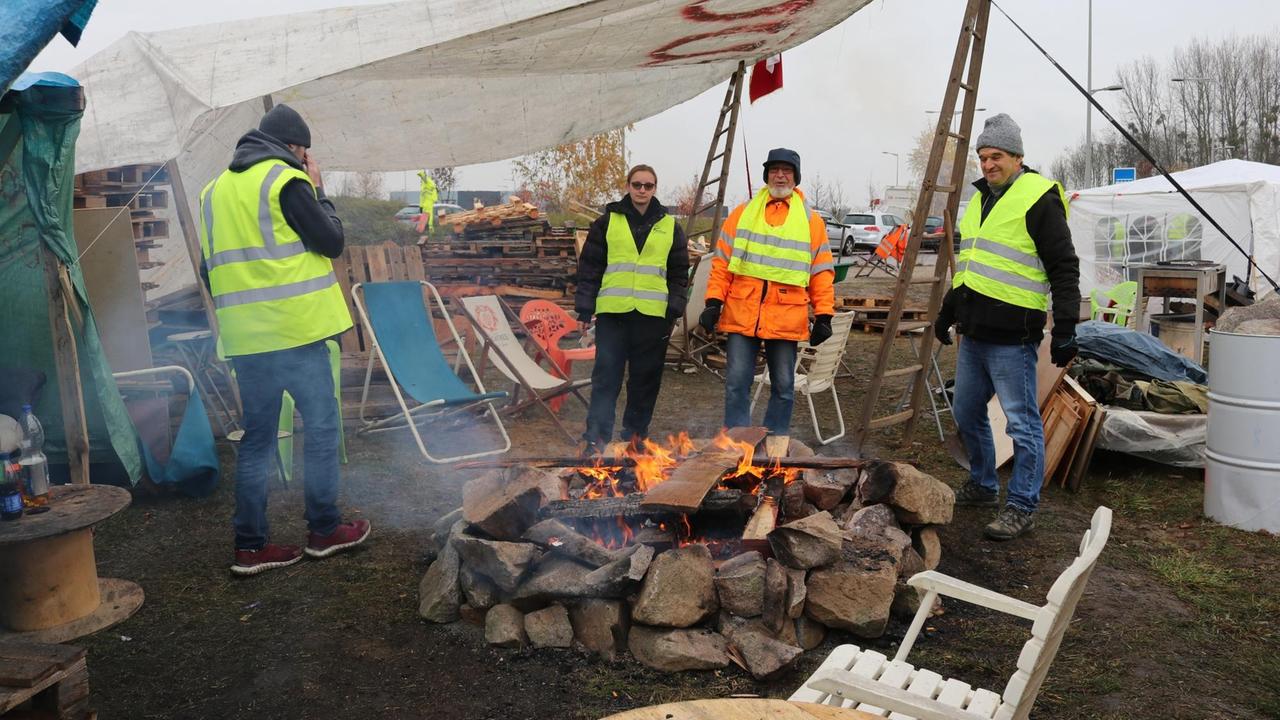 30.11.2018, Frankreich, Bernolsheim: Vier "Gelbwesten" wärmen sich in ihrem Protestcamp nahe Straßburg an einem Lagerfeuer. 30.11.2018, Frankreich, Bernolsheim: Vier "Gelbwesten" wärmen sich in ihrem Protestcamp nahe Straßburg an einem Lagerfeuer.