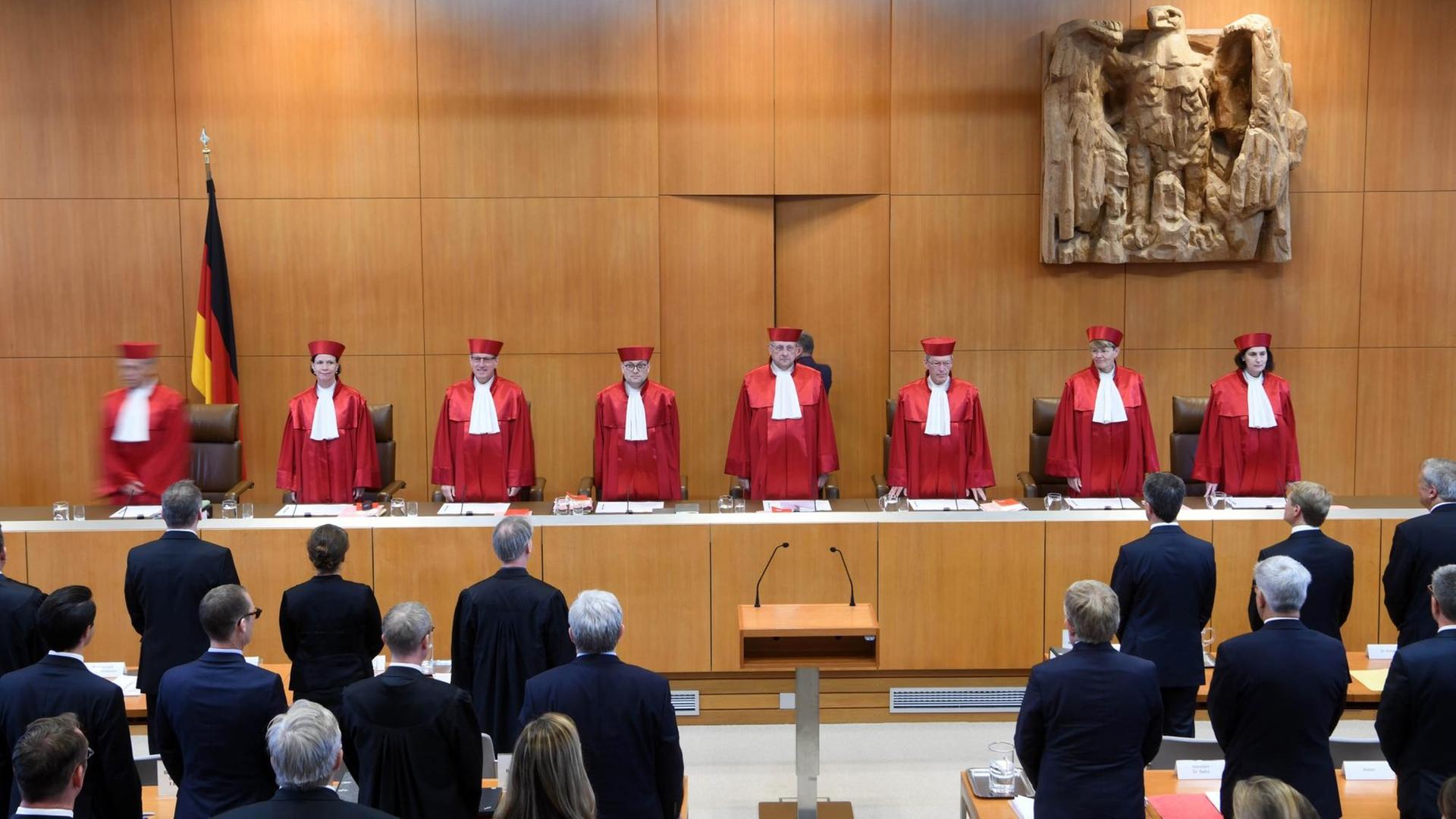Der Erste Senat des Bundesverfassungsgericht steht in roten Roben im Gerichtssaal in Karlsruhe. Der Erste Senat des Bundesverfassungsgericht steht in roten Roben im Gerichtssaal in Karlsruhe.