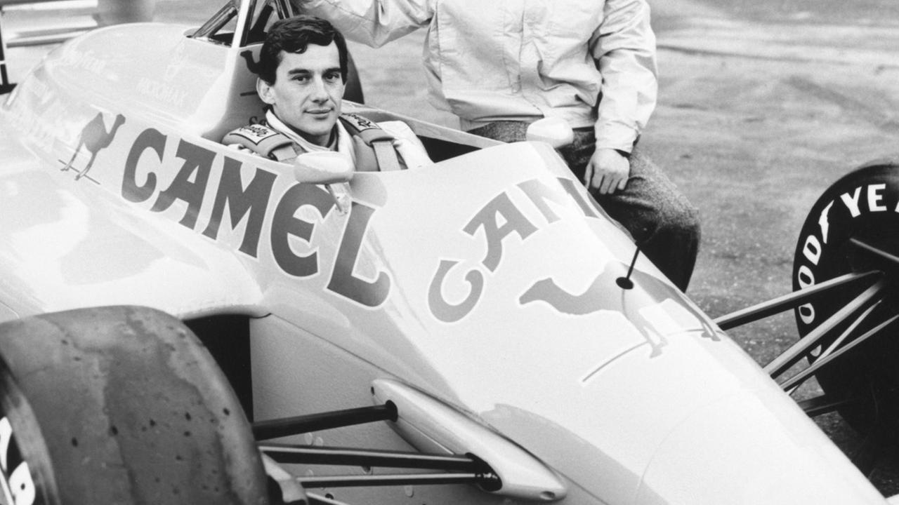 Der Brasilianer Ayrton Senna sitzt in einem Rennauto, neben ihm hockt sein japanischer Kollege Satoru Nakajima. Der Brasilianer Ayrton Senna sitzt in einem Rennauto, neben ihm hockt sein japanischer Kollege Satoru Nakajima.