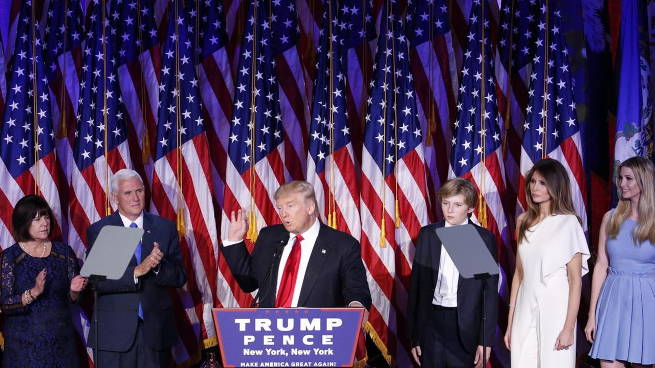 Donald Trump bei seiner Rede in New York nach seinem Wahlsieg, rechts neben ihm stehen seine Frau und einer seiner Söhne Donald Trump bei seiner Rede in New York nach seinem Wahlsieg, rechts neben ihm stehen seine Frau und einer seiner Söhne