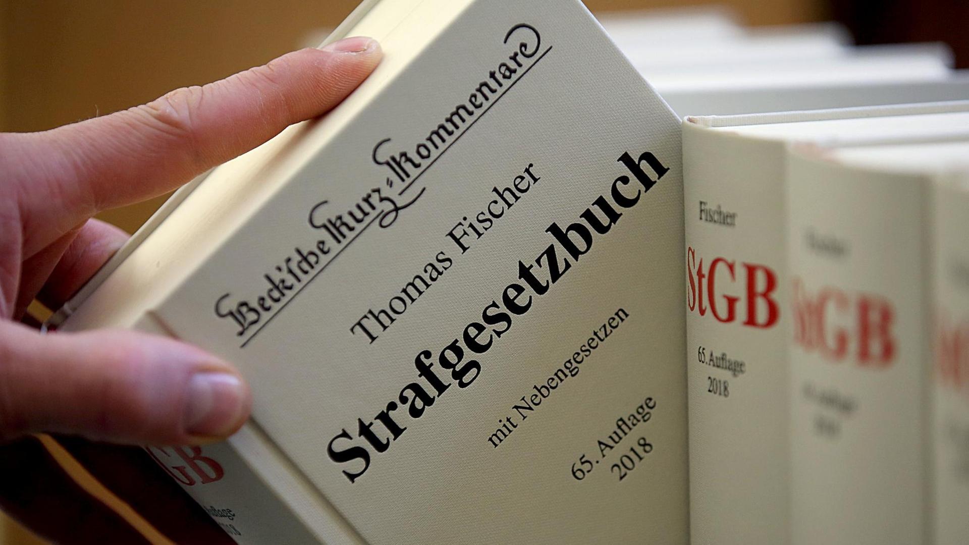 ILLUSTRATION - Ein Jurist nimmt am 24.01.2018 in Köln (Nordrhein-Westfalen) am Oberlandesgericht das Strafgesetzbuch aus dem Regal. ILLUSTRATION - Ein Jurist nimmt am 24.01.2018 in Köln (Nordrhein-Westfalen) am Oberlandesgericht das Strafgesetzbuch aus dem Regal.
