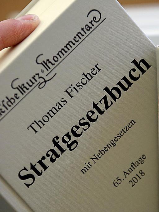 ILLUSTRATION - Ein Jurist nimmt am 24.01.2018 in Köln (Nordrhein-Westfalen) am Oberlandesgericht das Strafgesetzbuch aus dem Regal.