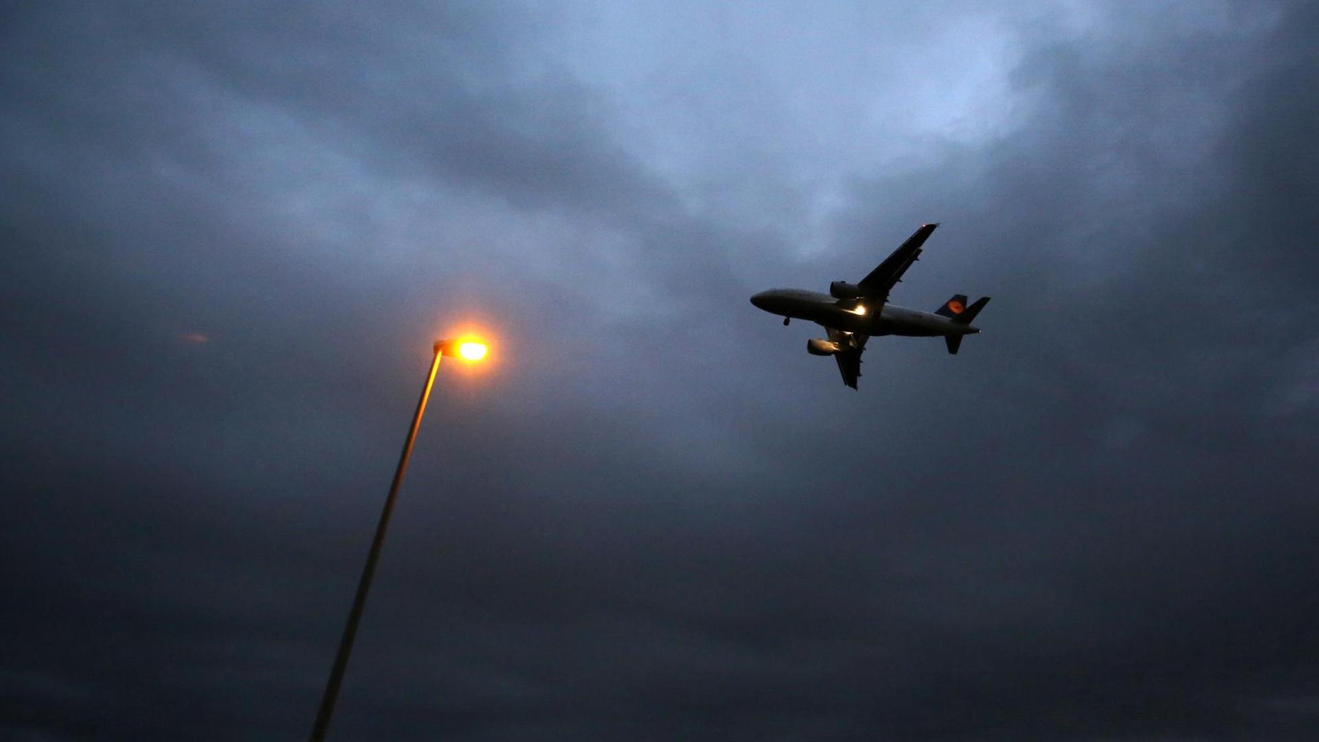 Ein Flugzeug der Lufthansa landet am 20.10.2014 am Flughafen in Frankfurt am Main (Hessen). Im Vordergrund ist eine Laterne zu sehen.
