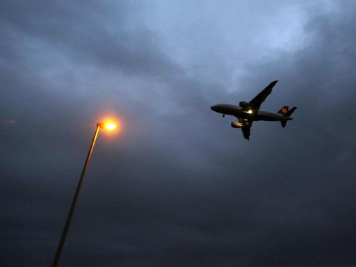 Ein Flugzeug der Lufthansa landet am 20.10.2014 am Flughafen in Frankfurt am Main (Hessen). Im Vordergrund ist eine Laterne zu sehen.