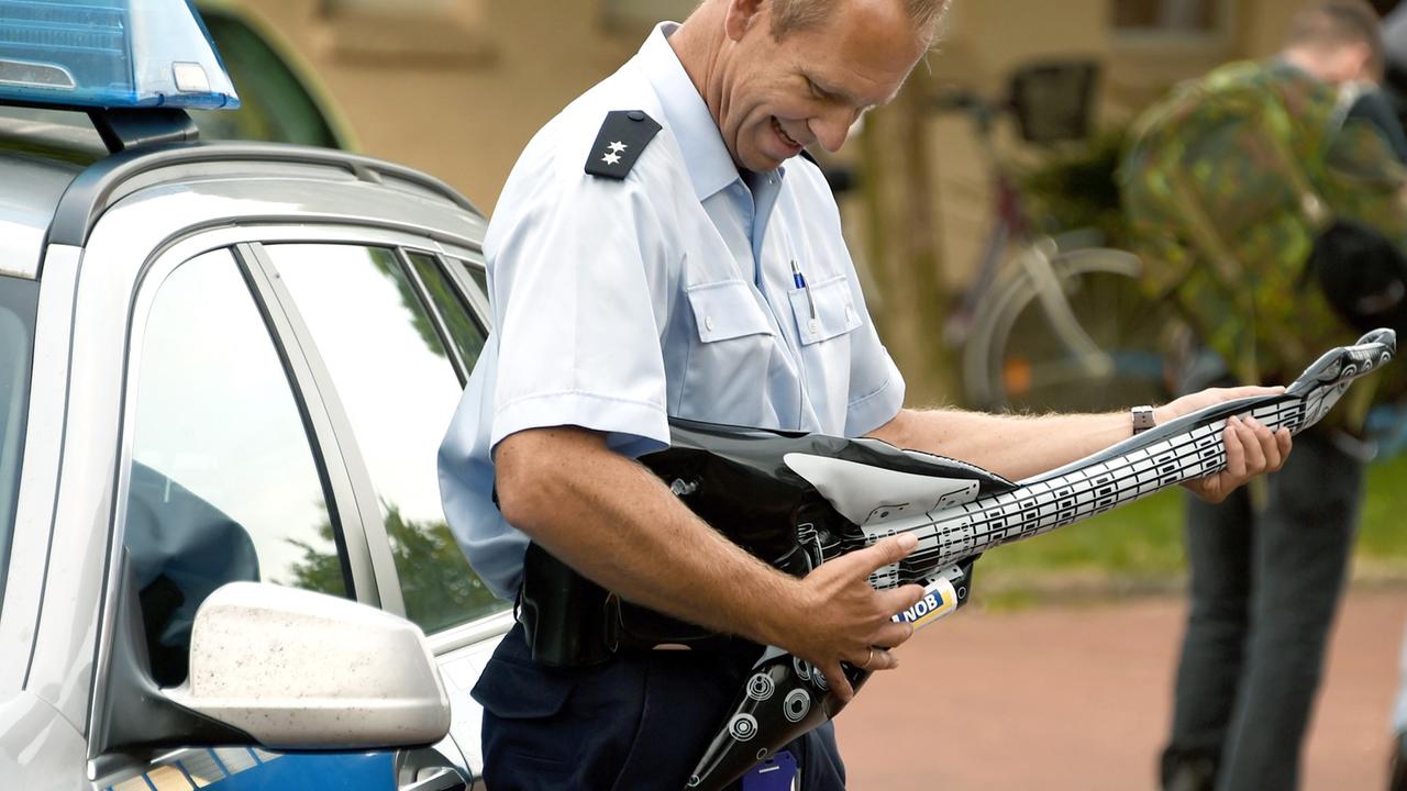 Ein Beamter der Bundespolizei spielt am 30. Juli 2014 in Itzehoe mit einer aufblasbaren Gitarre. Bis zum Samstag 2. August werden in der kleinen Gemeinde Wacken rund 75.000 Besucher zum Heavy Metal Festival "Wacken Open Air" erwartet. Ein Beamter der Bundespolizei spielt am 30. Juli 2014 in Itzehoe mit einer aufblasbaren Gitarre. Bis zum Samstag 2. August werden in der kleinen Gemeinde Wacken rund 75.000 Besucher zum Heavy Metal Festival "Wacken Open Air" erwartet.
