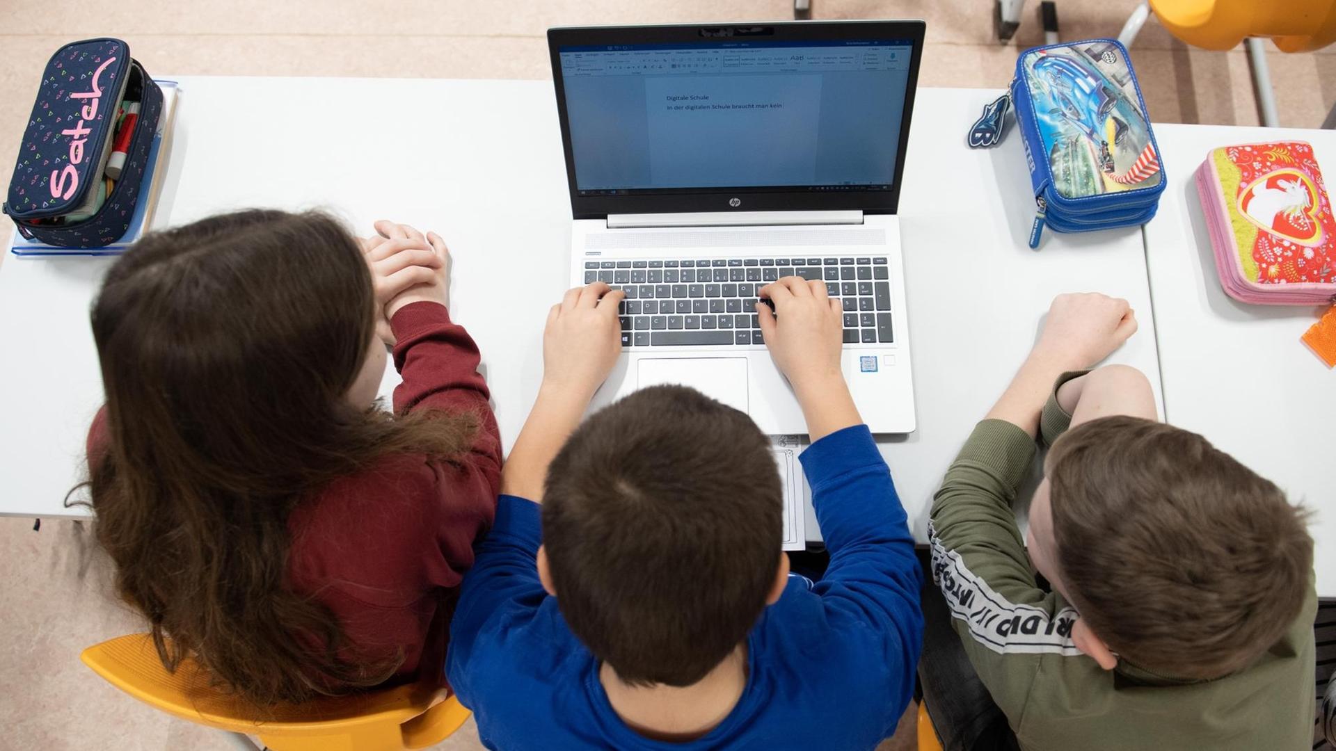 Schüler einer 3. Klasse sitzen in einem Klassenzimmer vor einem Laptop. Schüler einer 3. Klasse sitzen in einem Klassenzimmer vor einem Laptop.