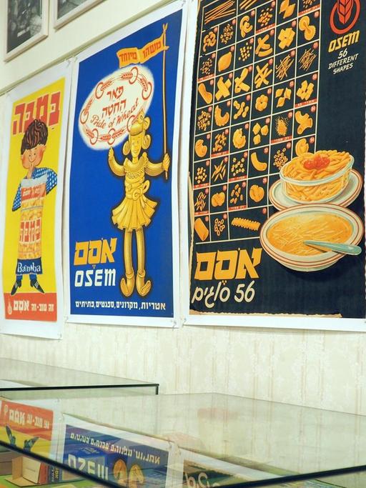 Mehrere Poster und Glasvitrinen zeigen Dinge aus der Zeit der 1930er bis in die 1950er.