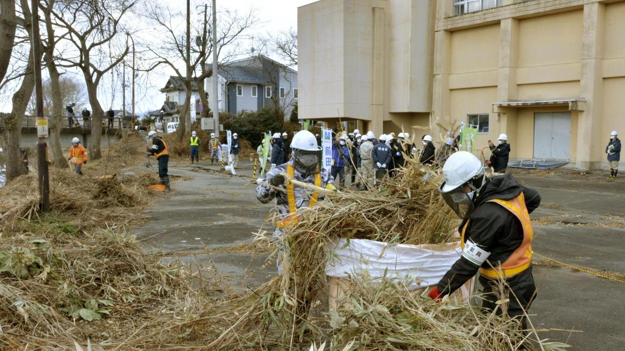 Arbeiter in Schutzkleidung beginnen am 25.12.2017 in Futaba, Präfektur Fukushima (Japan) mit den Dekontaminationsarbeiten auf dem radioaktiv belasteten Gelände. Die japanische Regierung will das Gebiet ab Frühjahr 2022 wieder bewohnbar machen. 