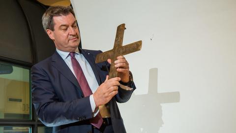 Der bayerische Ministerpräsident Markus Söder hält ein Kreuz