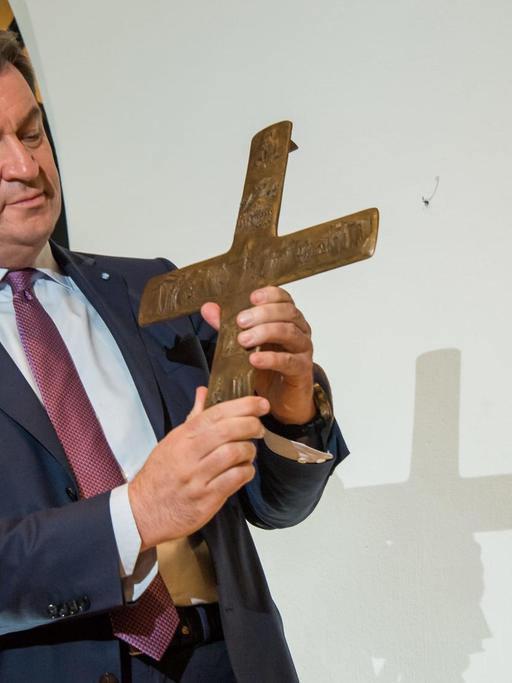 Der bayerische Ministerpräsident Markus Söder hält ein Kreuz