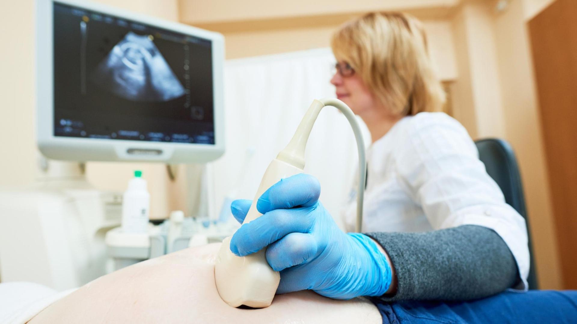 Eine Ärztin führt einen Ultraschall bei einer Schwangeren durch.