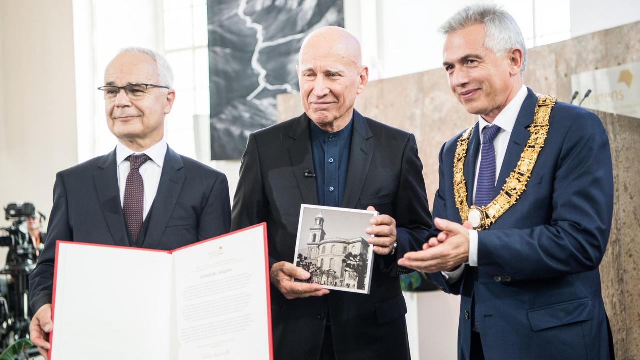 Heinrich Riethmüller (l-r), Vorsteher des Börsenvereins des Deutschen Buchhandels, Sebastião Salgado, Fotograf, und Peter Feldmann (SPD), Oberbürgermeister von Frankfurt am Main, stehen nach der Preisverleihung in der Paulskirche zusammen. Heinrich Riethmüller (l-r), Vorsteher des Börsenvereins des Deutschen Buchhandels, Sebastião Salgado, Fotograf, und Peter Feldmann (SPD), Oberbürgermeister von Frankfurt am Main, stehen nach der Preisverleihung in der Paulskirche zusammen.