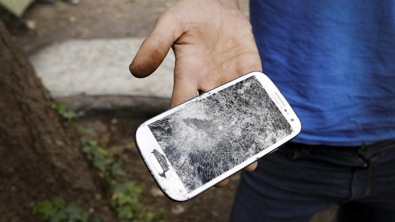 Ein Flüchtling in Bosnien und Herzegowina zeigt sein zerstörtes Handy