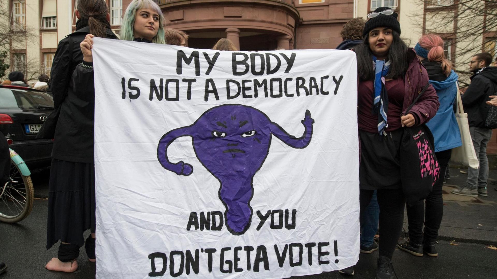Mit einem Plakat sprechen sich Demonstrantinnen am 24.11.2017 vor dem Amtsgericht in Gießen (Hessen) für die Selbstbestimmung von Frauen beim Thema Abtreibung aus. Auf ihrem Plakat steht "My body is not a democracy - and you don't get a vote" ("Mein Körper ist keine Demokratie - und Du bekommst keine Stimme"). Im Gericht muss sich die Ärztin Kristina Hänel verantworten. Sie soll auf ihrer Homepage für Abtreibung geworben haben und sich damit strafbar haben.