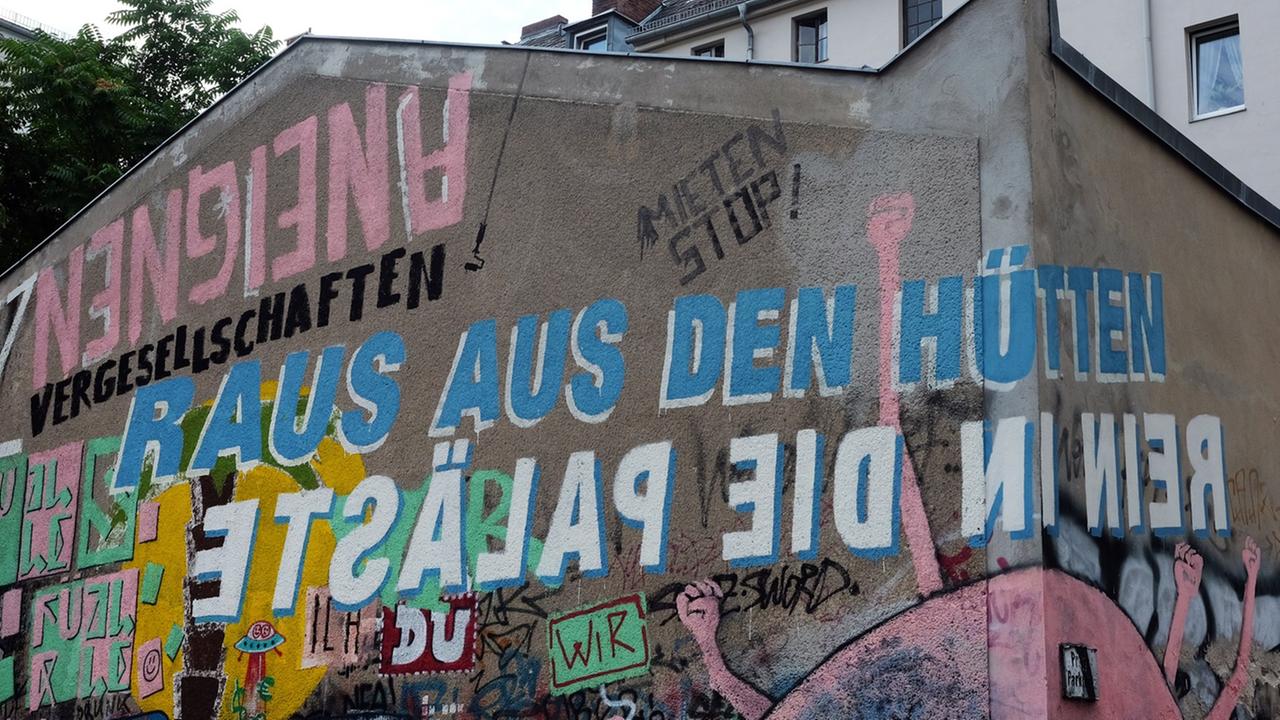 "Raus aus den Hütten. Rein in die Paläste" steht in Berlin an einer Häuserwand in der Gneisenaustraße in Kreuzberg, aufgenommen 2017 "Raus aus den Hütten. Rein in die Paläste" steht in Berlin an einer Häuserwand in der Gneisenaustraße in Kreuzberg, aufgenommen 2017