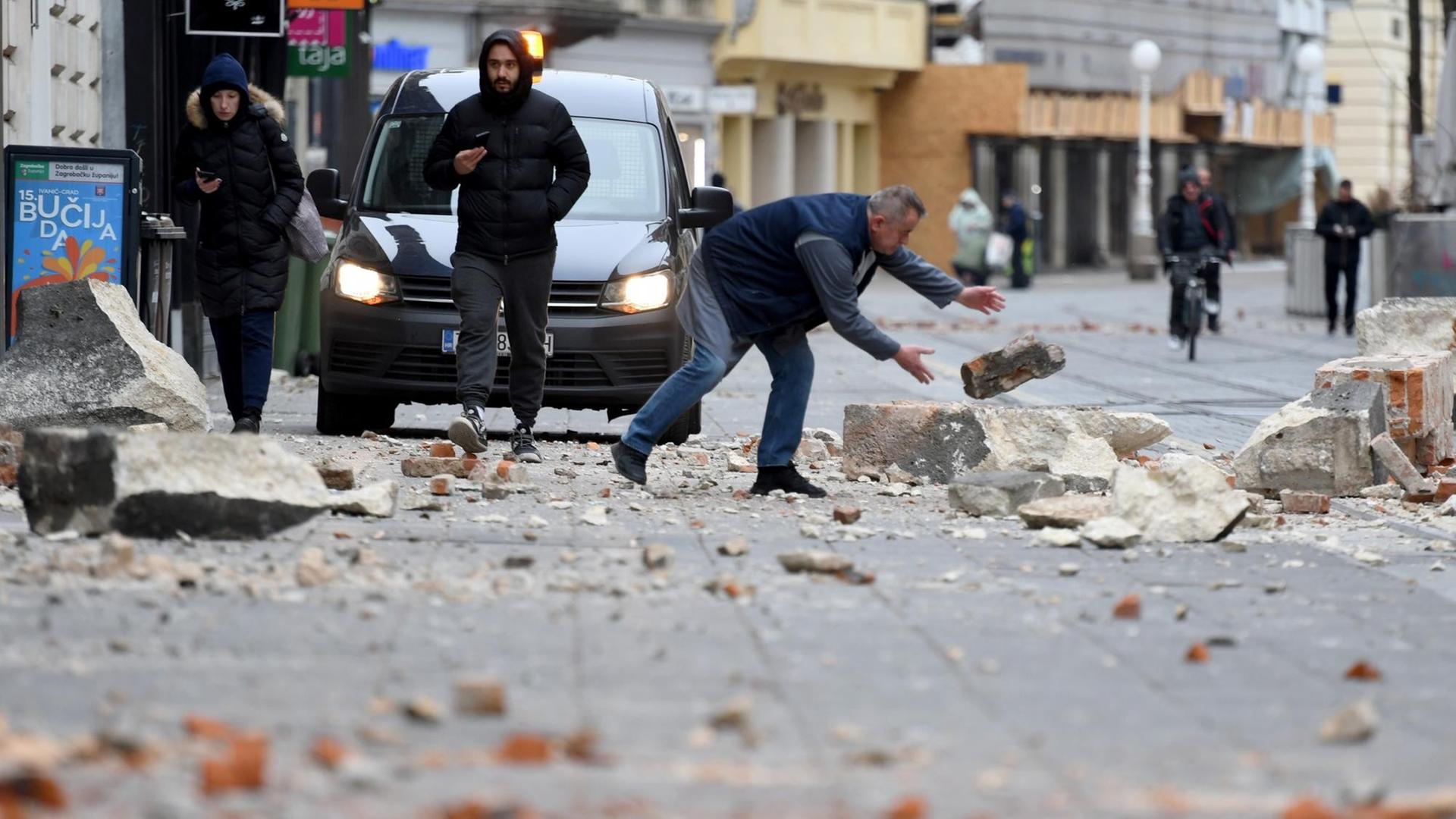 Ein Mann räumt nach dem Erd-Beben in Kroatien Steine von der Straße.