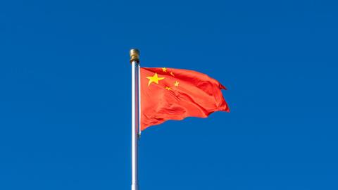 Die rote Flagge der Volksrepublik China vor blauem Himmel.