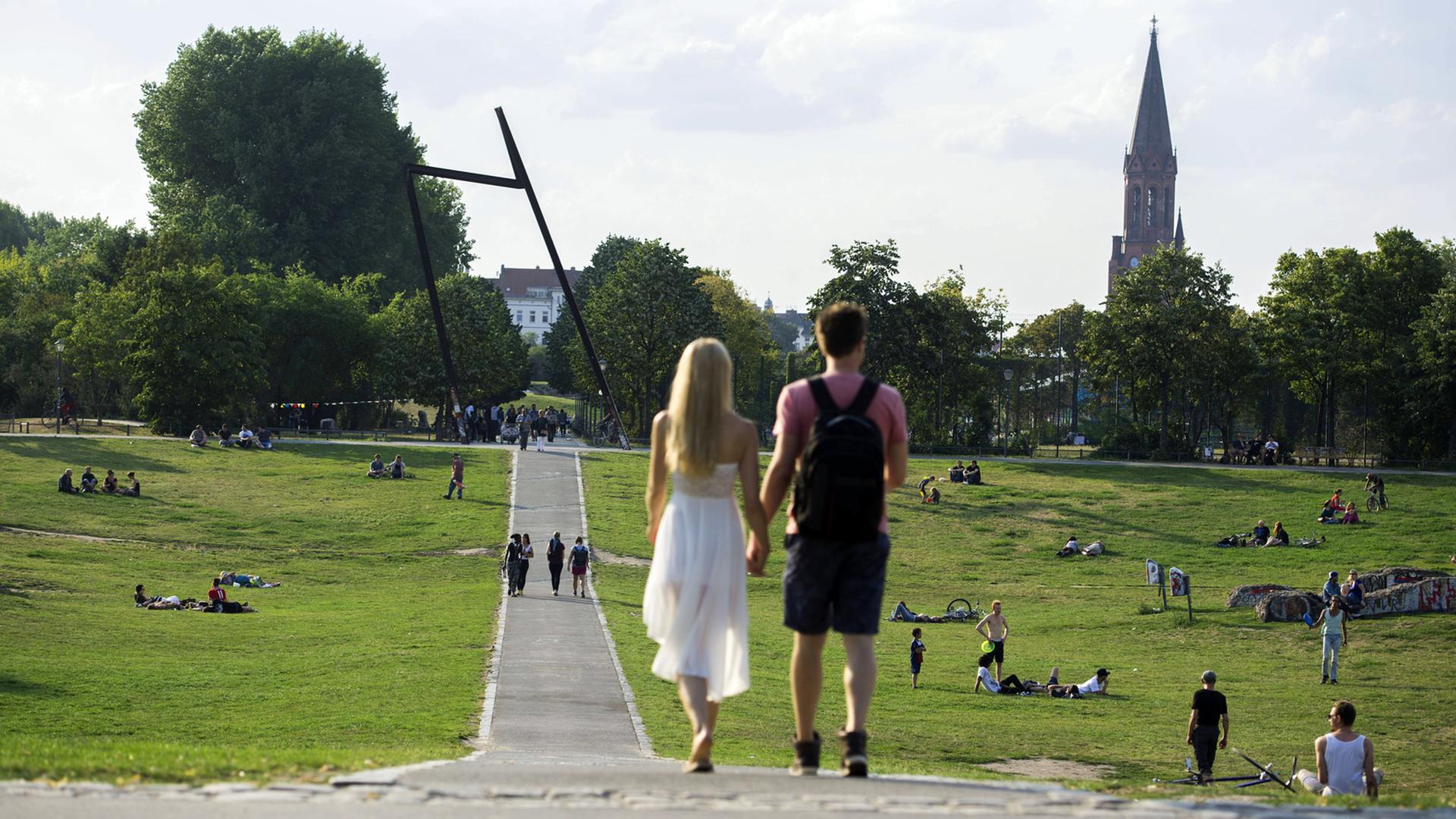 Ein Paar läuft Händchen haltend in der Abendsonne durch den Görlitzer Park in Berlin-Kreuzberg Ein Paar läuft Händchen haltend in der Abendsonne durch den Görlitzer Park in Berlin-Kreuzberg