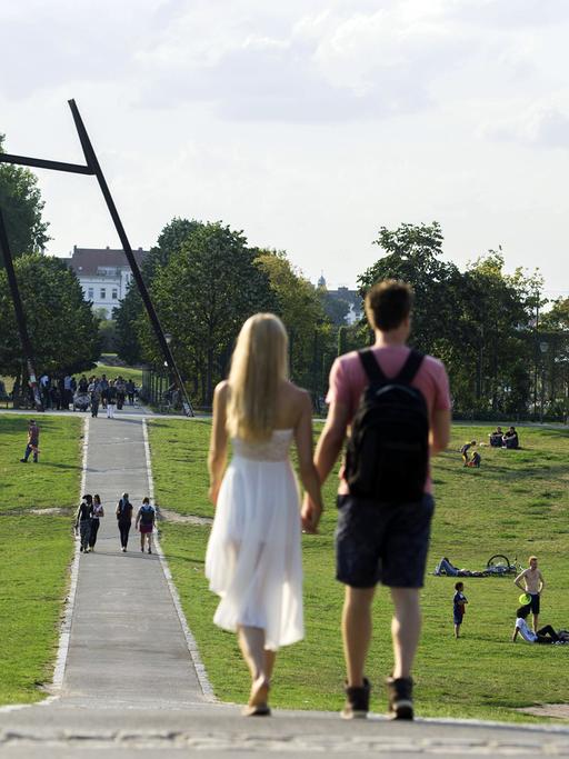 Ein Paar läuft Händchen haltend in der Abendsonne durch den Görlitzer Park in Berlin-Kreuzberg