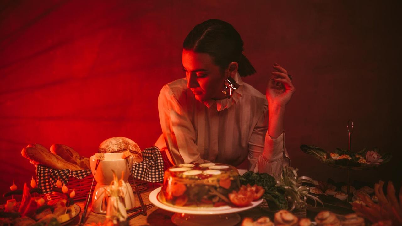 Die Musikerin Nadine Shah sitzt an einem Tisch voller Speisen. Die Musikerin Nadine Shah sitzt an einem Tisch voller Speisen.