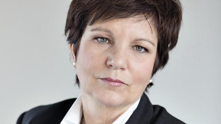 Eine Frau mit kurzen dunklen Haaren schaut in die Kamera. Eine Frau mit kurzen dunklen Haaren schaut in die Kamera.