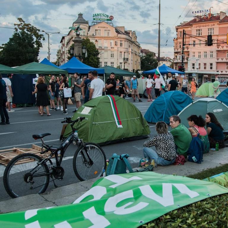 Demonstranten sitzen am Straßenrand und blockieren mit aufgeschlagenen Zelten die Straßen.