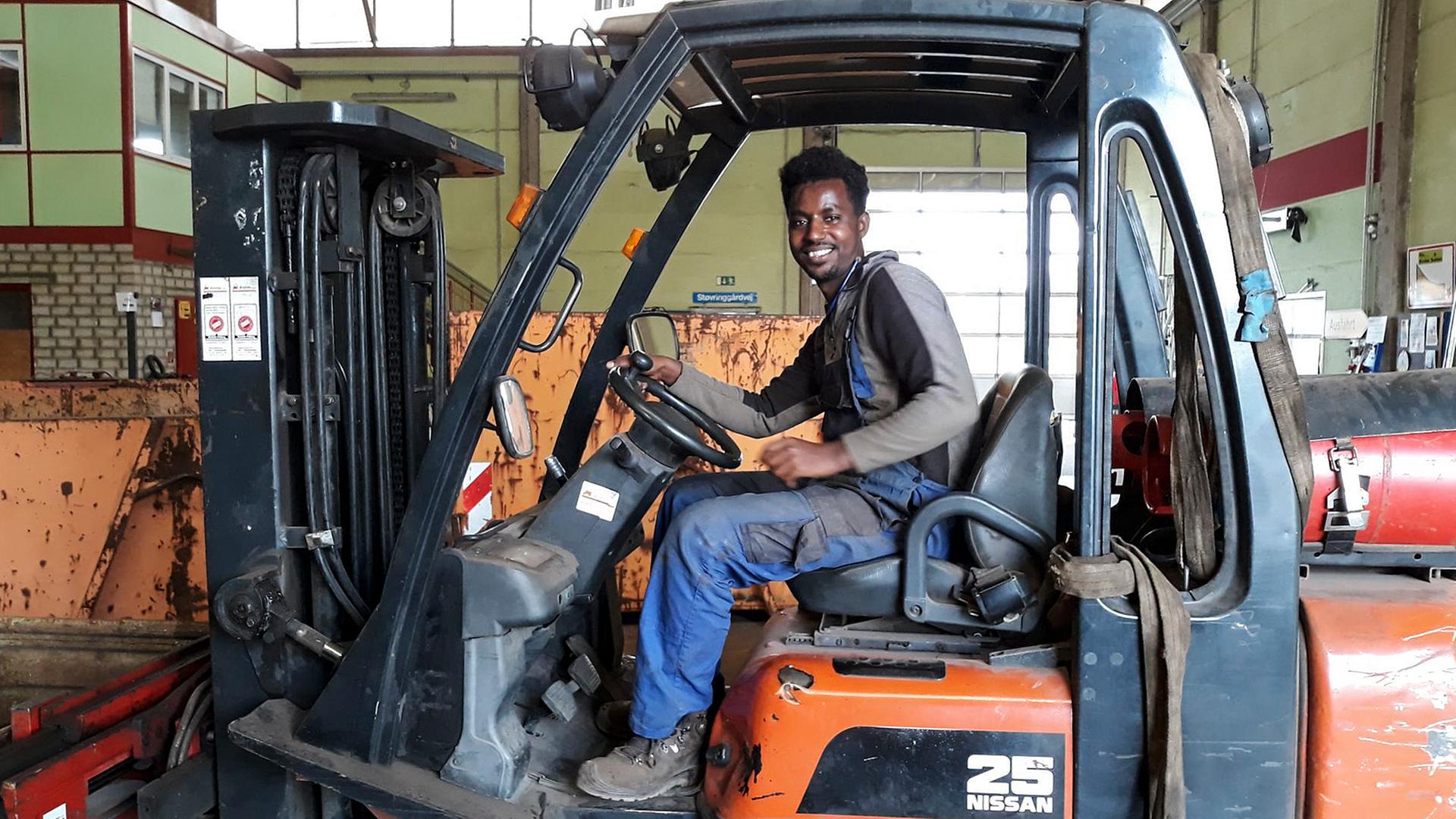 Ein junger Mann aus Eritrea sitzt am Steuer eines Gabelstaplers Ein junger Mann aus Eritrea sitzt am Steuer eines Gabelstaplers