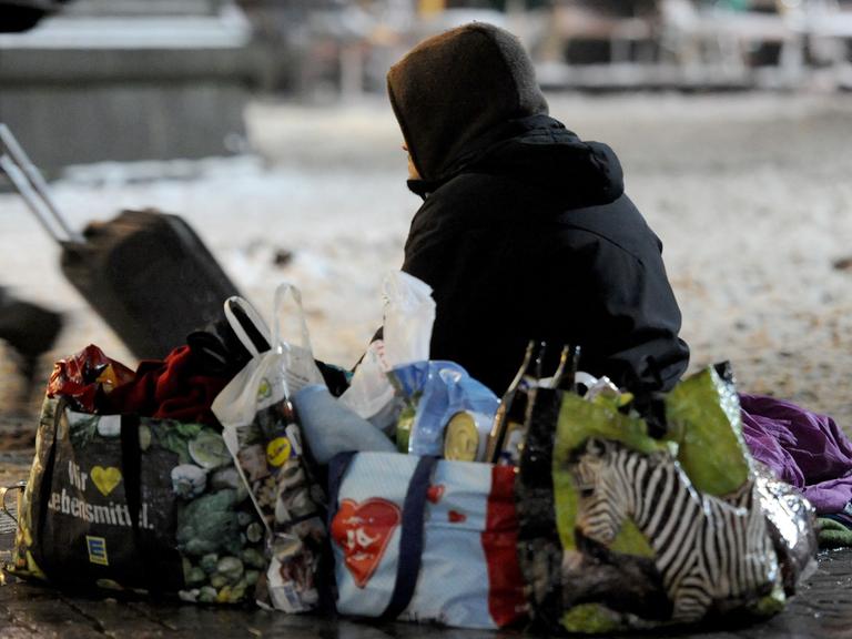 Ein obdachloser Mann sitzt im Winter auf dem Vorplatz des Hauptbahnhofes in Bremen.