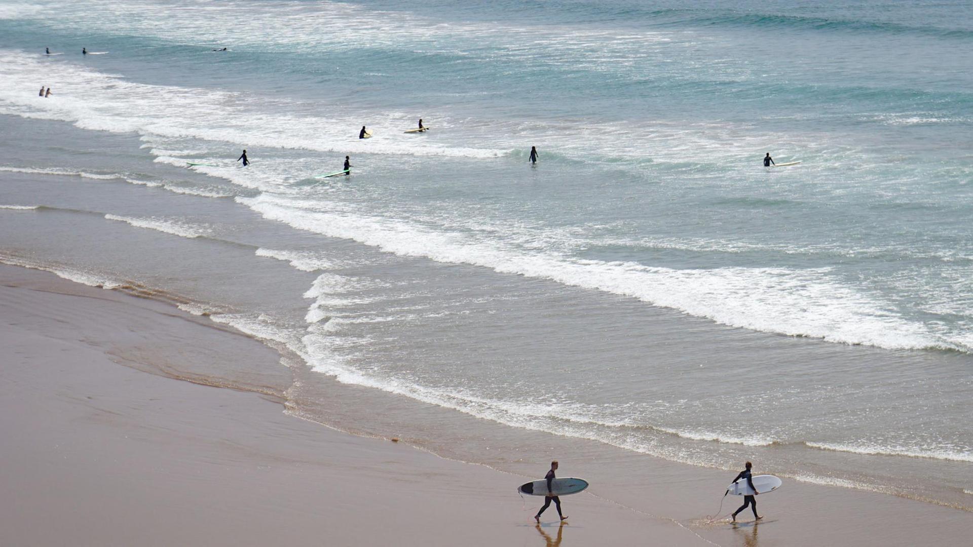Touristen surfen und baden am 29.03.2016 in Taghazout (Marokko) am Strand an der Atlantikküste.